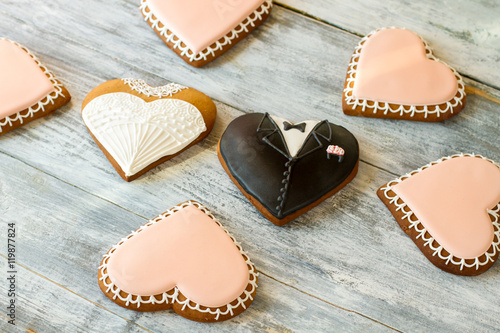 Wedding cookies on wooden background. Heart biscuits with glaze. Newlyweds and witnesses. Love is everywhere.