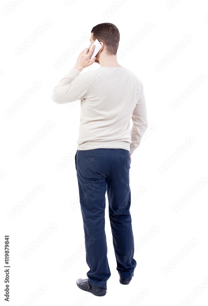 back view of standing young man with tablet computer in the hands of. bearded man in a white sweater warm white talking on a smartphone. back view of standing young man with tablet computer in the hands of. bearded man in a white sweater warm white talking on a smartphone.