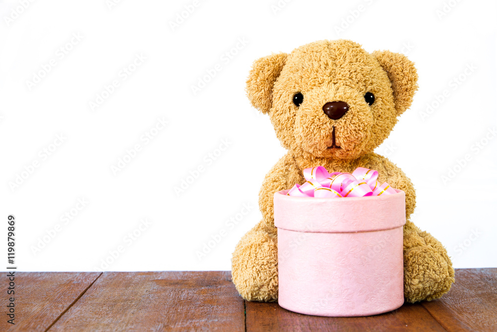 Obraz premium Teddy Bear holding gift box on wood