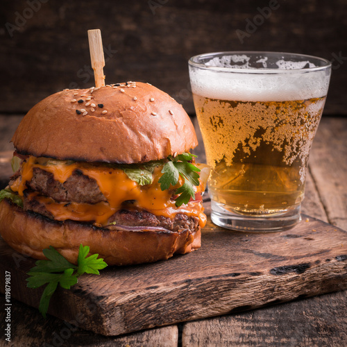 Fresh and tasty hamburger with a beer on a wooden table.