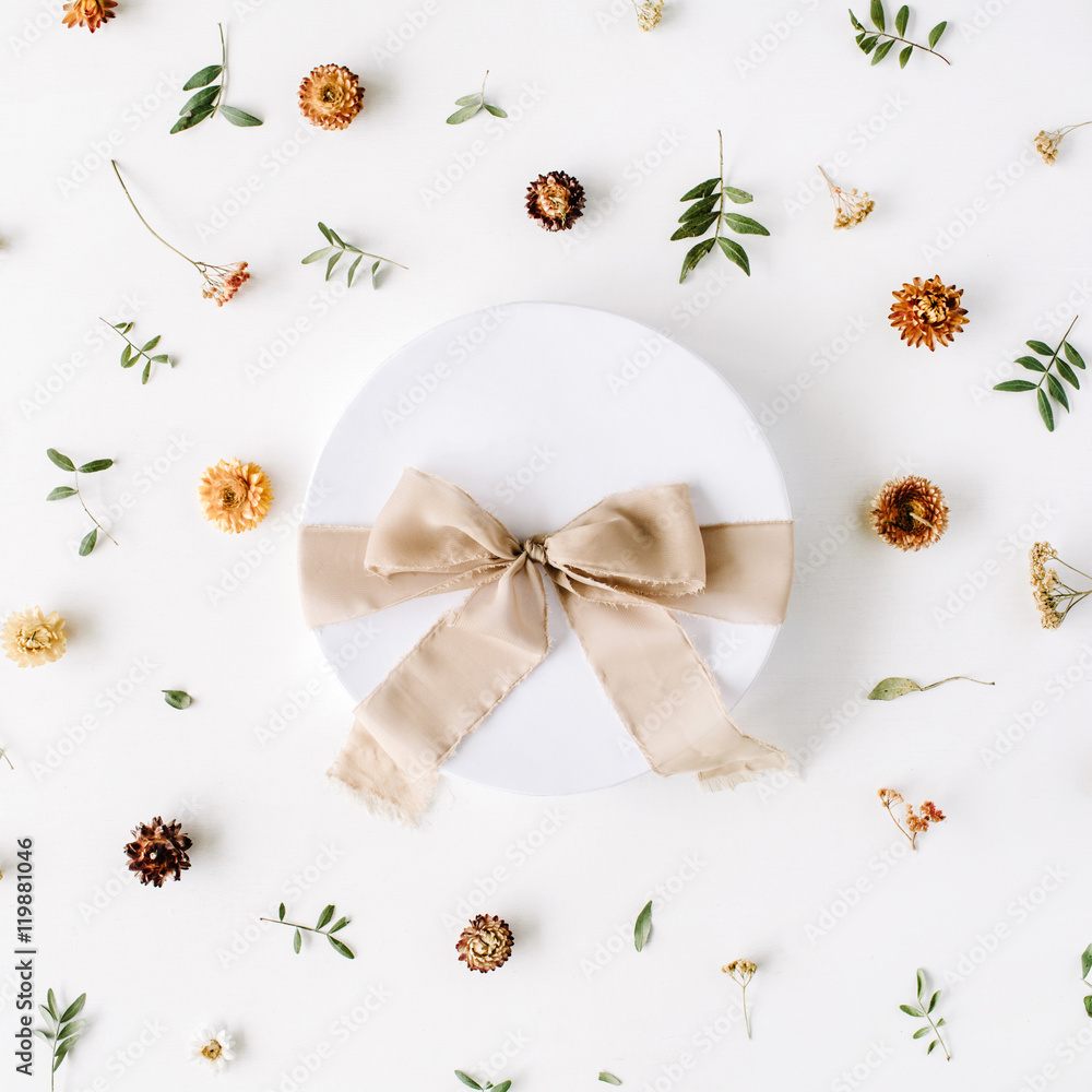 white gift cardboard box with brown bow on white background with floral composition. flat lat, top view white gift cardboard box with brown bow on white background with floral composition. flat lat, top view