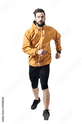 Athlete in ocher jacket running towards camera. Toned desaturated full body length portrait isolated on white studio background.