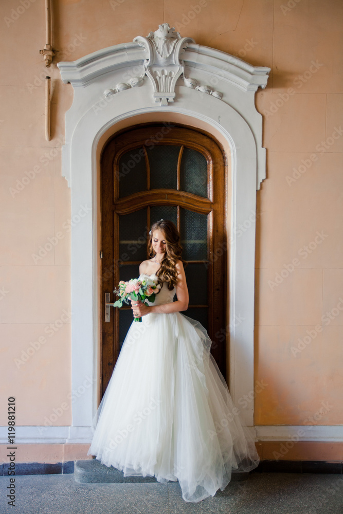 Beautiful happy bride is standing with her tender bouquet