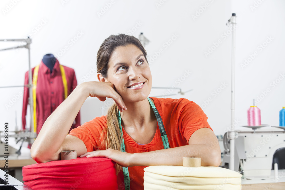 Smiling Female Tailor Leaning On Fabric Spools Smiling Female Tailor Leaning On Fabric Spools
