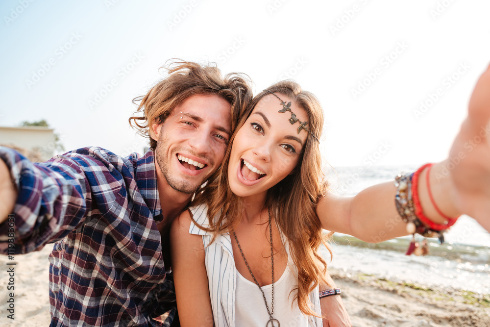 Couple taking selfie and laughing on the beach Couple taking selfie and laughing on the beach