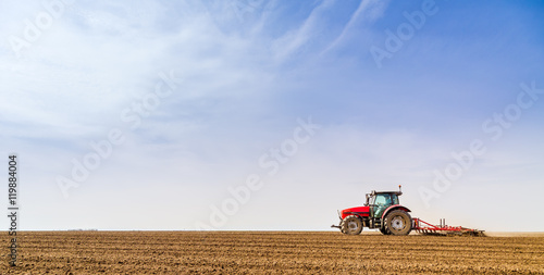 Farmer in tractor preparing land with seedbed cultivator photo