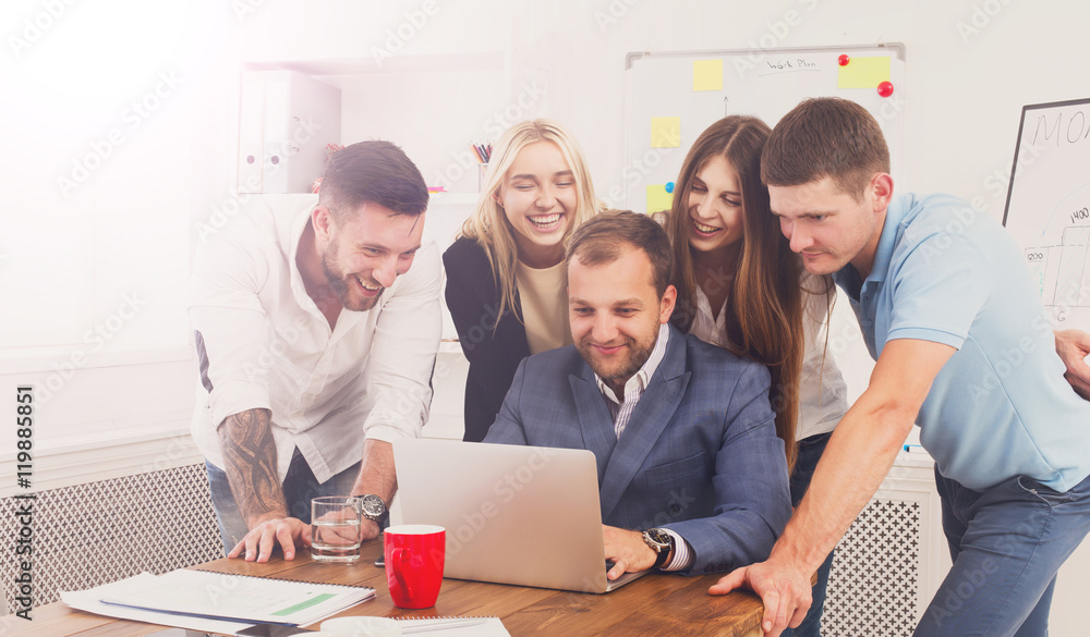 Happy business people team together look at laptop in office Happy business people team together look at laptop in office