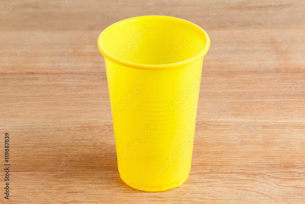 Empty yellow plastic glass on wooden Empty yellow plastic glass on wooden