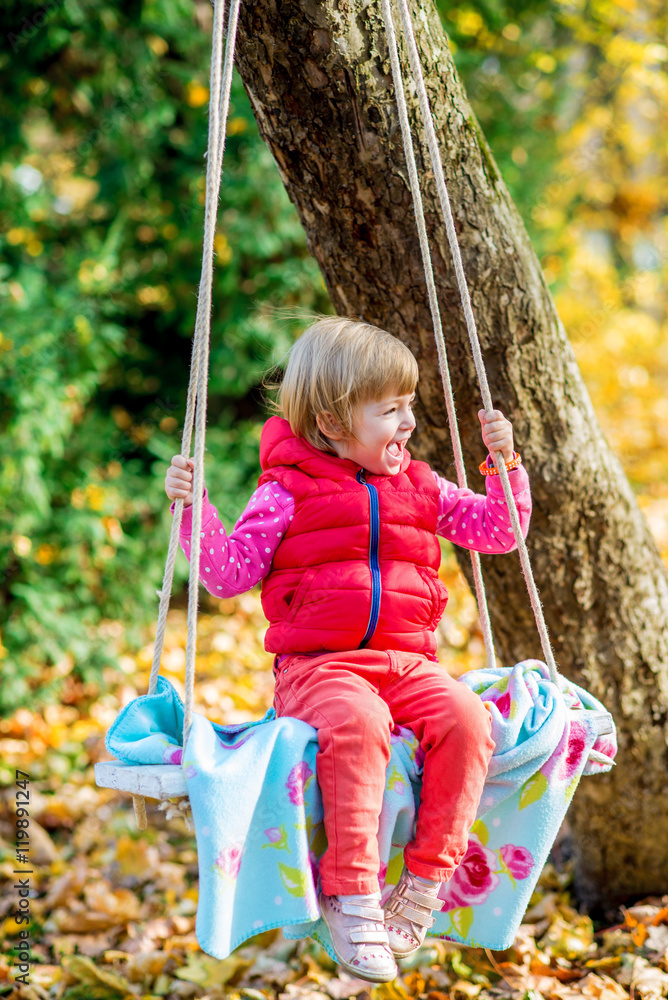 Adorable little girl having fun on a swing on beautiful autumn day Adorable little girl having fun on a swing on beautiful autumn day