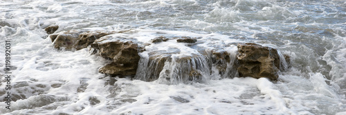 Breaking waves with foam on the rocky coast