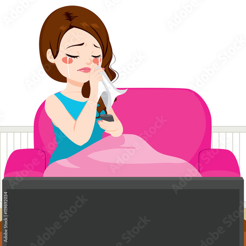 Young woman crying while watching TV movie lying on couch with blanket