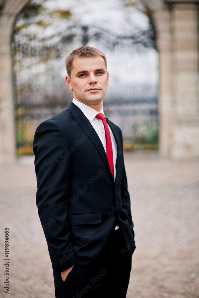 Handsome groom in red tie is standing alone Handsome groom in red tie is standing alone