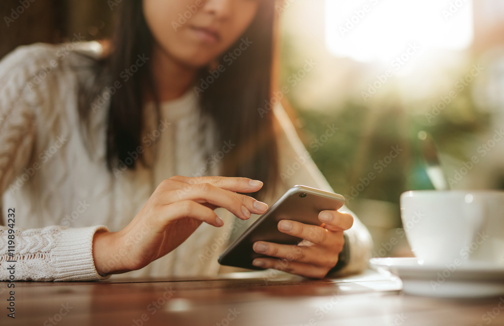 Woman sitting at a table using mobile phone Woman sitting at a table using mobile phone