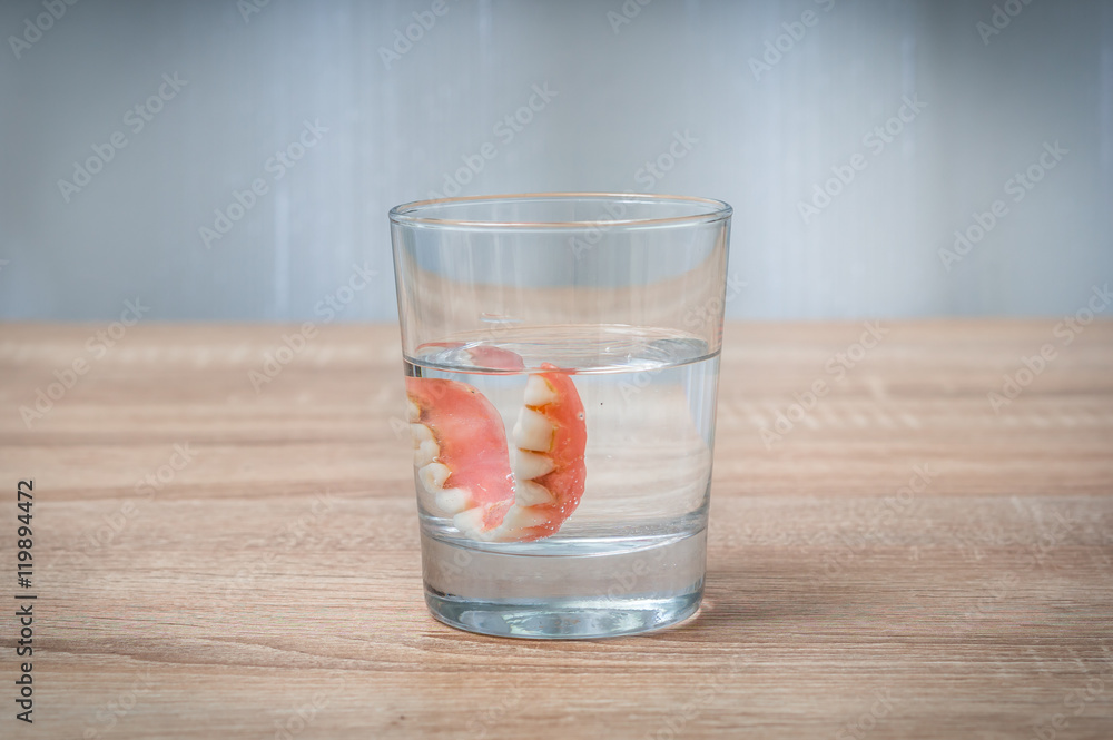 False teeth swim in transparent water glass False teeth swim in transparent water glass