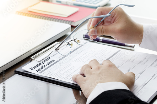 Businessman or HR Manager review a blank  Employment Application form with Magnifier and computer laptop, digital tablet, calculator, note book. job vacancy concept.