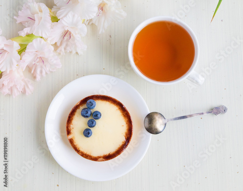 Cheese cake with blueberry and cup of tea on white background, top view