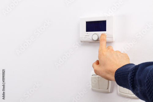 Men hand setting the temperature on control panel of DHW or central heating.