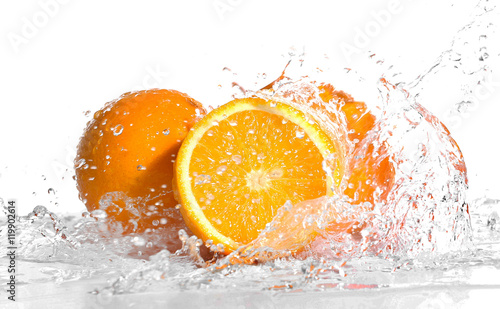 Fresh oranges in splashing water isolated on white