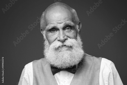 Elderly bearded man in stylish suit on grey background photo