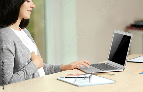Pregnant woman sitting at table with laptop