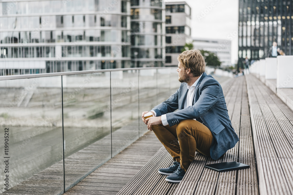 Businessman sitting on bridge having coffee break Businessman sitting on bridge having coffee break