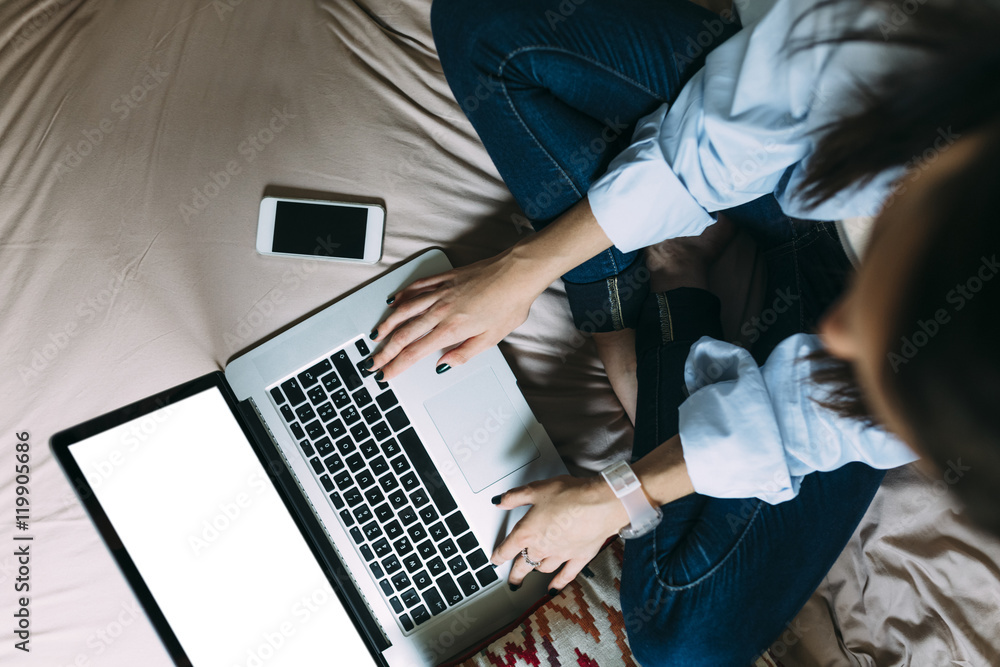 Young woman using smartphone and laptop on bed Young woman using smartphone and laptop on bed