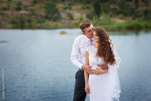 beautiful young couple walking near the lake on the wedding day