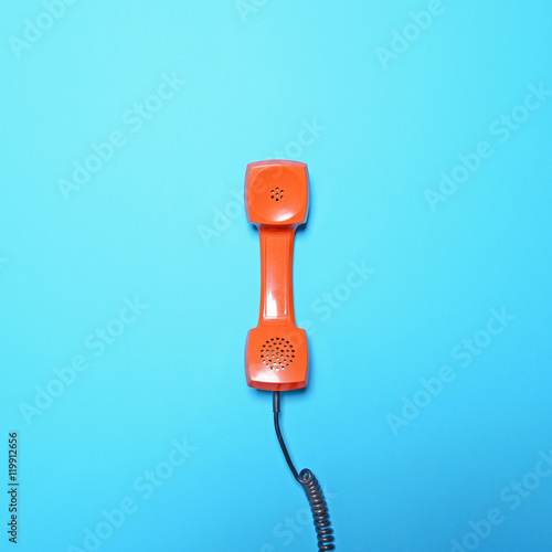Retro orange telephone tube on blue background - Flat lay