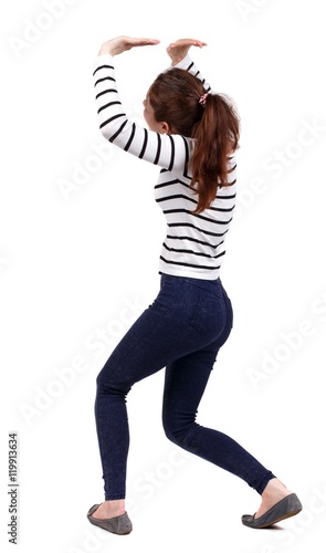 back view of woman protects hands from what is falling from above. Girl in striped sweater holding something over his head.