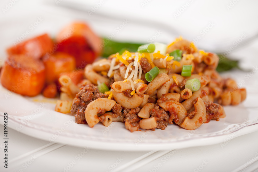 Homemade hamburger macaroni with honey glazed carrots and asparagus cooked in avocado oil macro shot on white