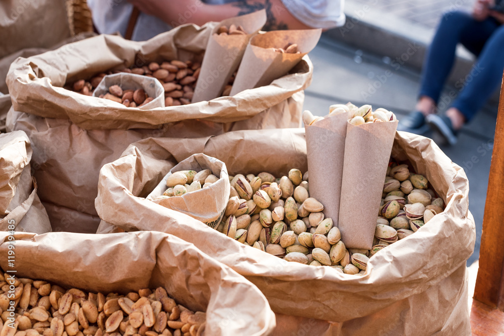 Salted peanuts, pistachios and almonds in a paper bags closeup. Street food.