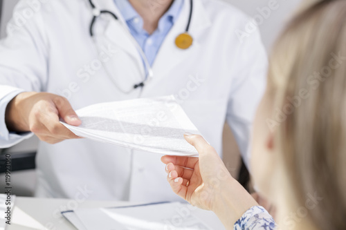 doctor give a document to patient photo