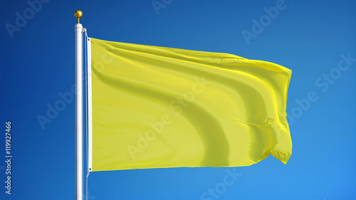 Bright yellow flag waving against clean blue sky, close up, isolated with clipping path mask alpha channel transparency
