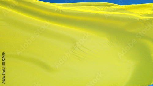 Bright yellow flag waving against clean blue sky, close up, isolated with clipping path mask alpha channel transparency