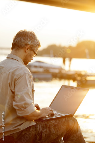 Man working on computer in sunset outdoor