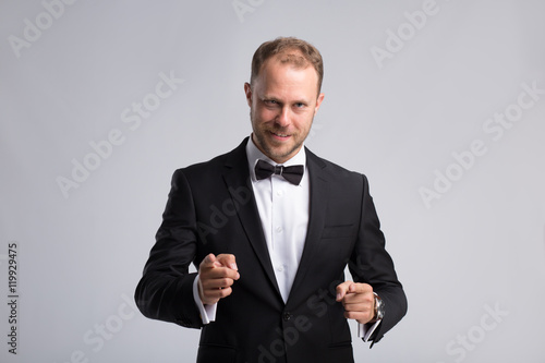 Handsome businessman in classic suit make confirmation gesture on gray background