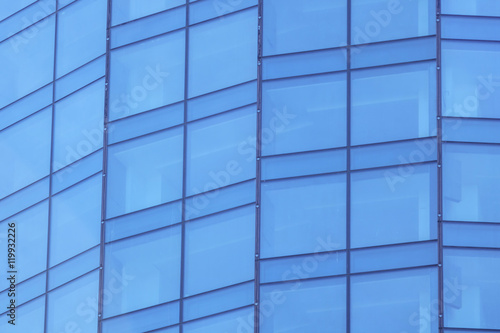 The glass facade of a skyscraper with a mirror reflection of sky windows