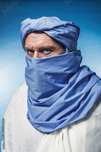 Berber man wearing blue turban with white robe. Studio shot.