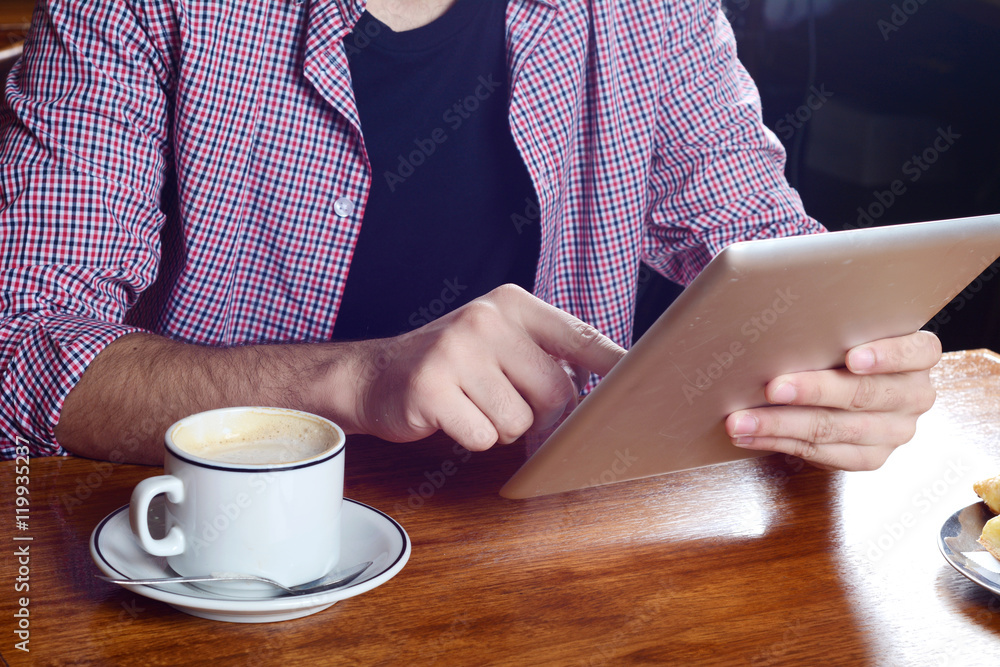 Young man using digital tablet at a cafe.
