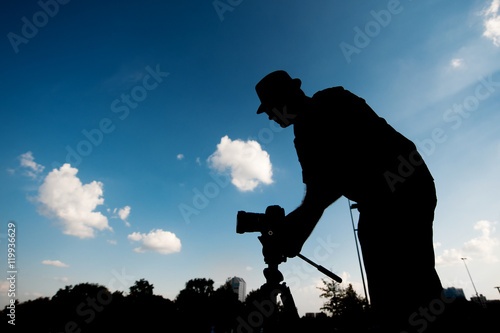 silhouette of a man with camera on the sky background