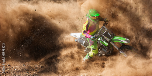 Fototapeta Motocross rider racing in a large cloud of dust and debris