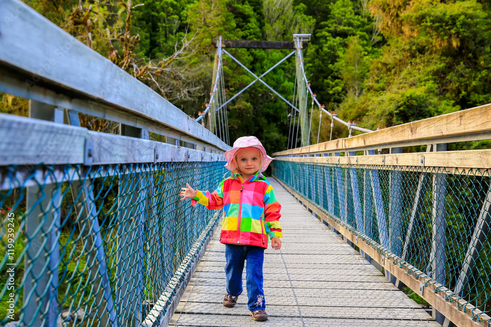 Obraz premium Little girl walks on the bridge. Haast, New Zealand