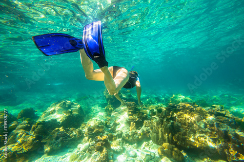 Young female snorkeling in tropical sea. Woman apnea swims in coral reef.