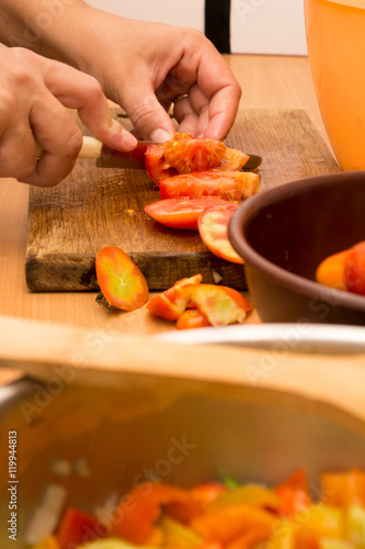 Cutting tomato on a wooden plate