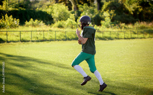 Brutal man with a long beard and mustache in the shape of an American football player with helmet and Ball on the training ground