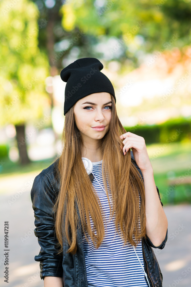 Beautiful millennial teenage girl with headphones and beanie hat in park in  autumn Stock Photo | Adobe Stock