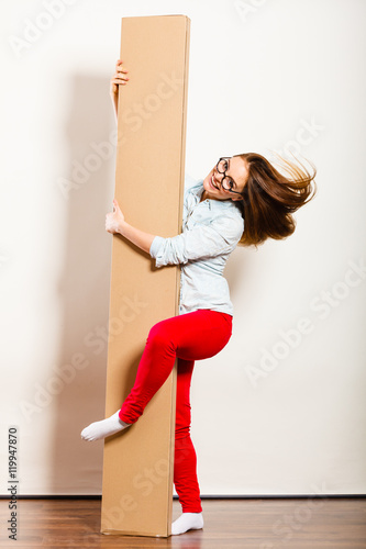 Fototapeta Naklejka Na Ścianę i Meble -  Funny woman moving into apartment holding box.