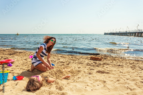 Mother and daughter playing on beach.