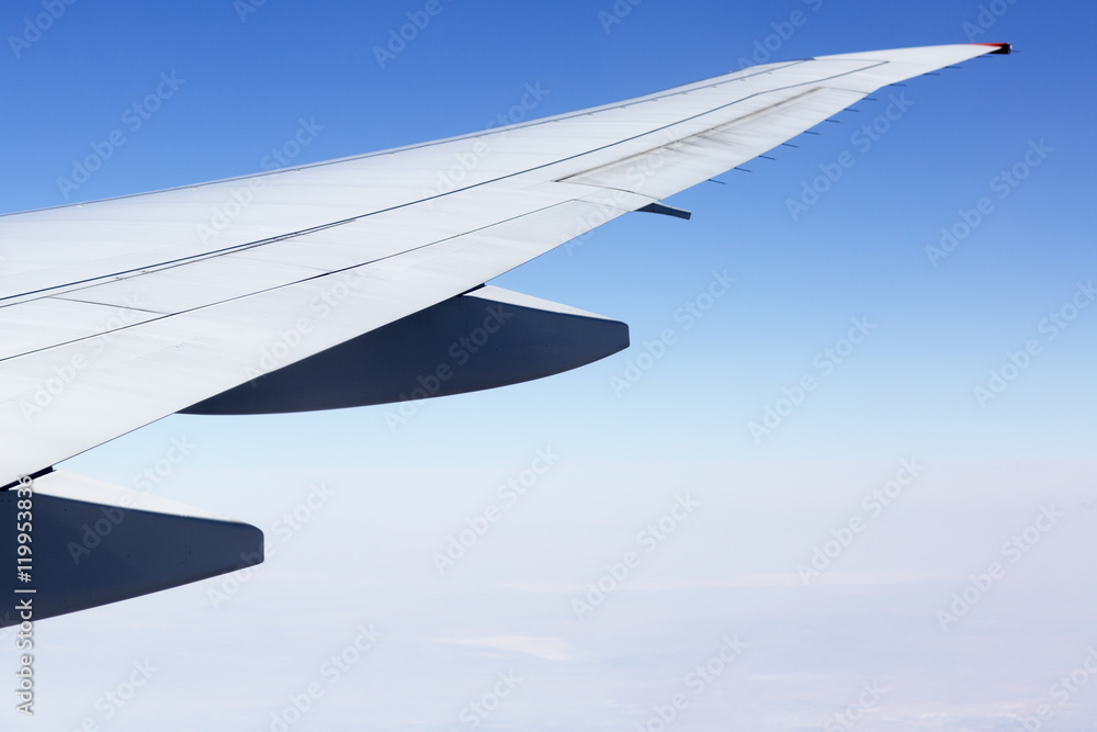 The wing of the plane on sky background during sunset. Air clouds illuminated by the rays of the sun. The wing of the plane on sky background during sunset. Air clouds illuminated by the rays of the sun.