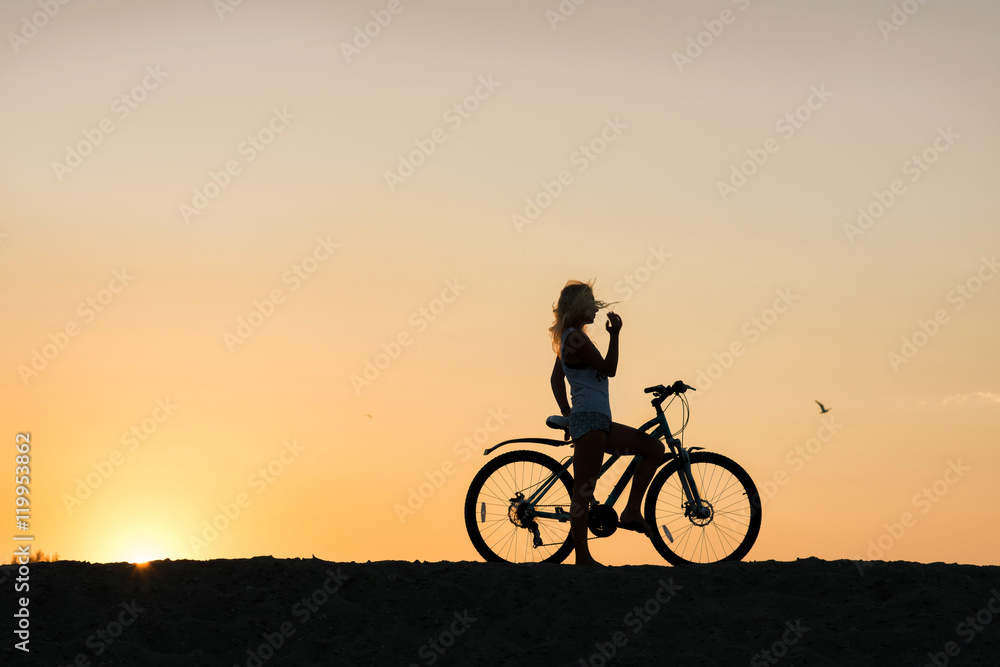 Young woman with bicycle enjoying sunset. Taking in the beauty of it all...